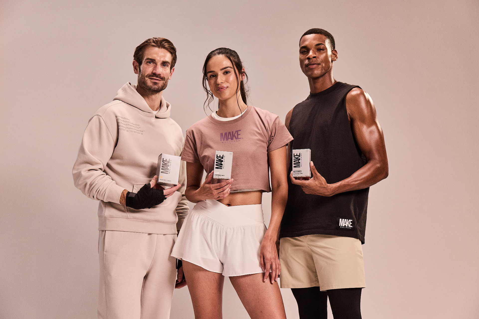 Two men and a woman holding MAKE Wellness products