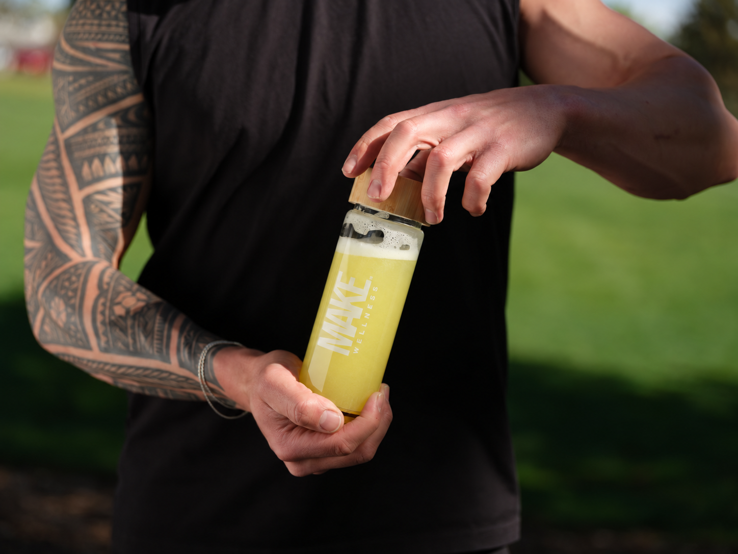 A man opening a MAKE Wellness bottle outdoors after training